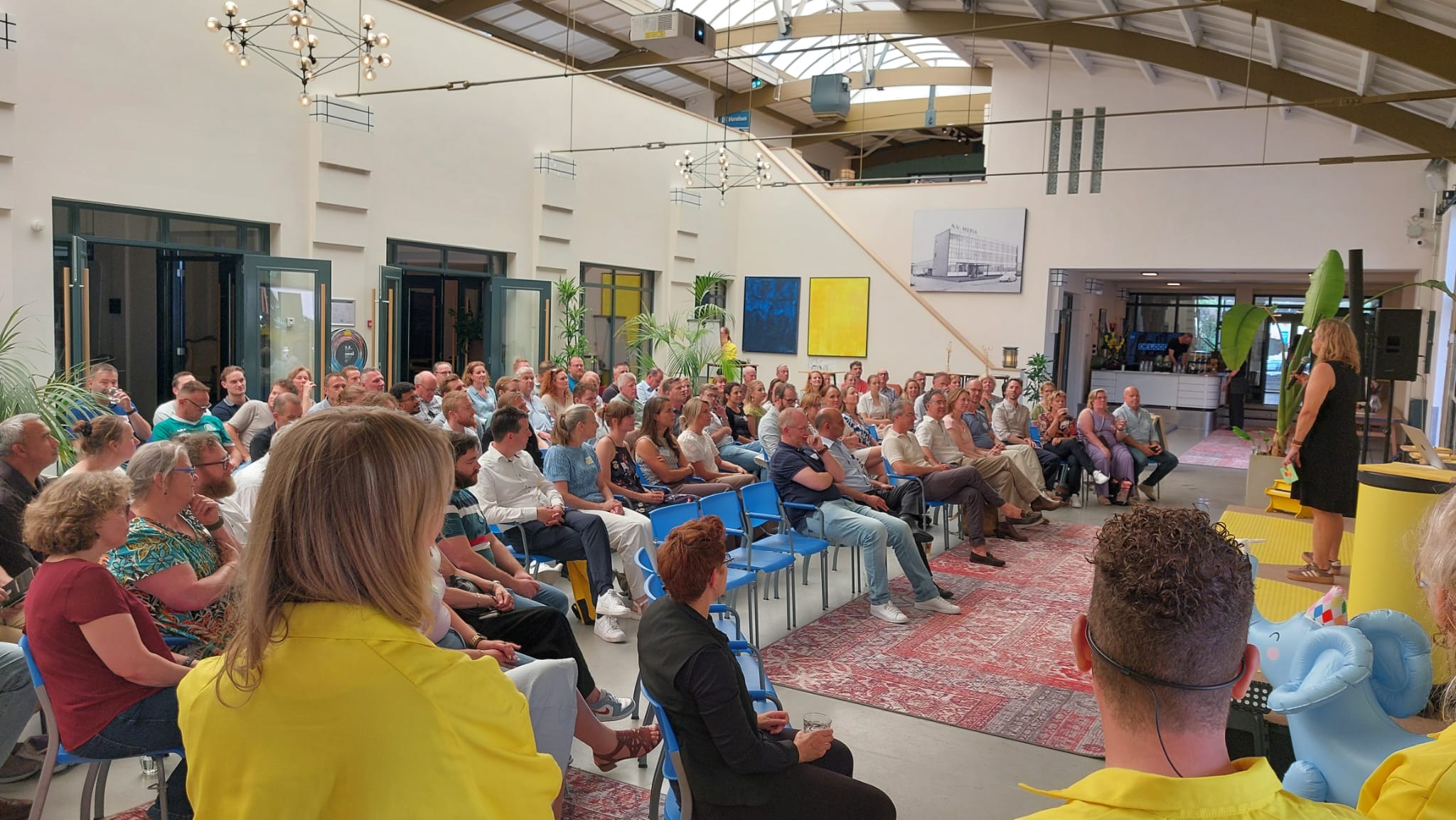 Groep mensen die in een bijeenkomst zitten.
